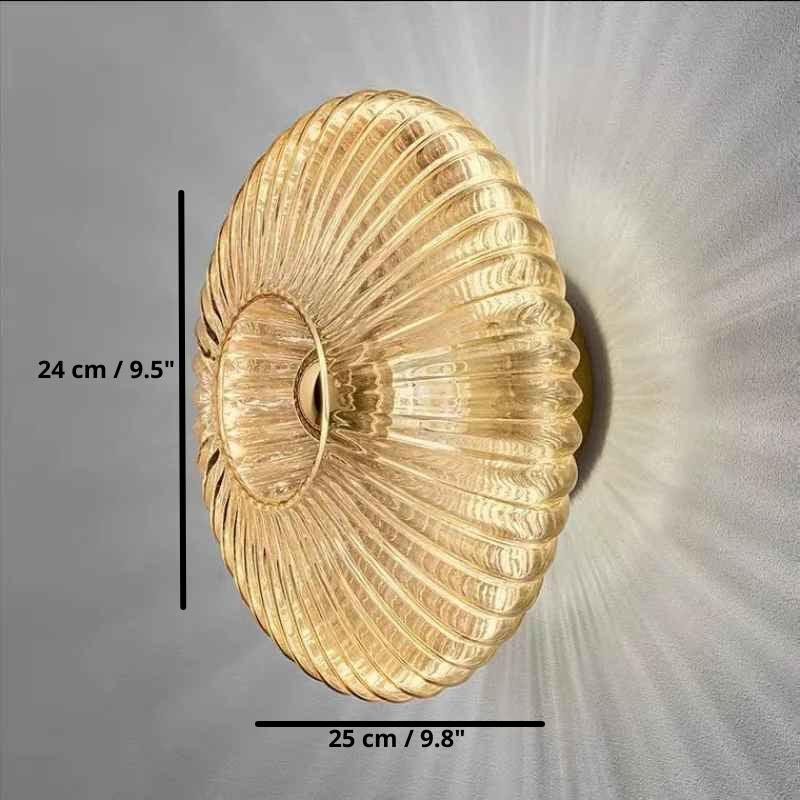 Gold glass wall sconce lamp, 24 cm by 25 cm, casting patterned light on wall.