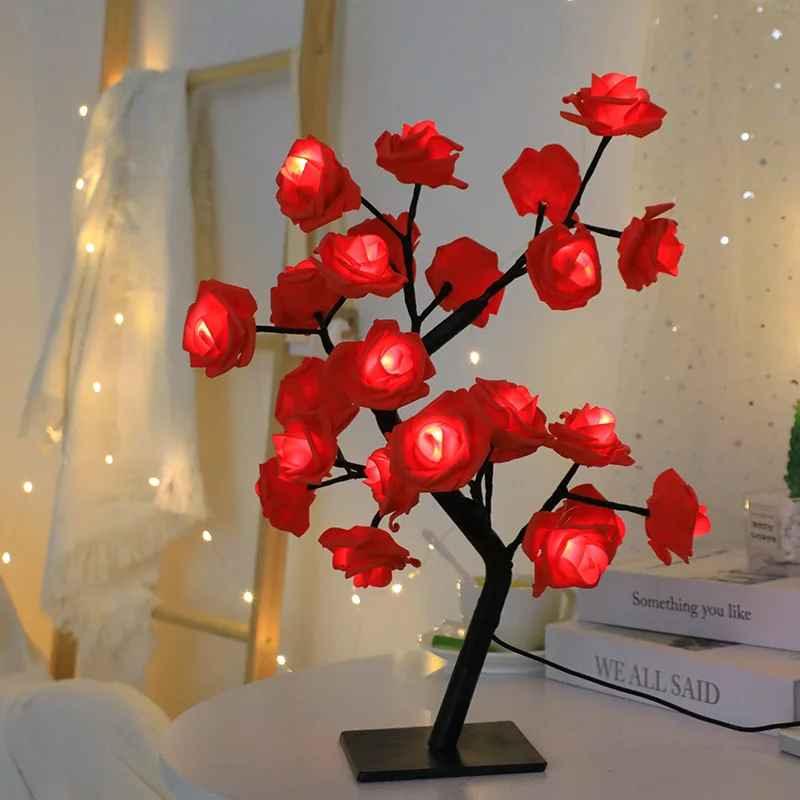 Red rose flower LED lamp on a table with fairy lights and decorative books in the background