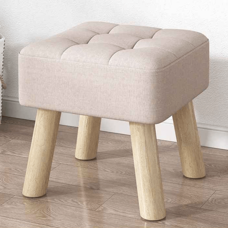Beige ottoman with wooden legs on a wooden floor