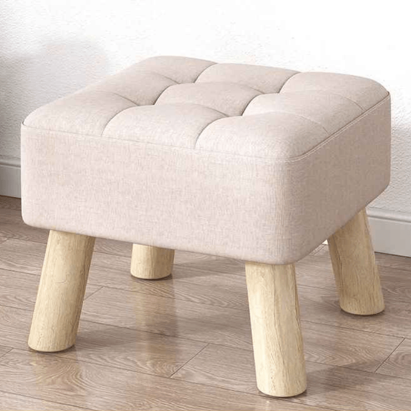 Beige ottoman with wooden legs on a wooden floor