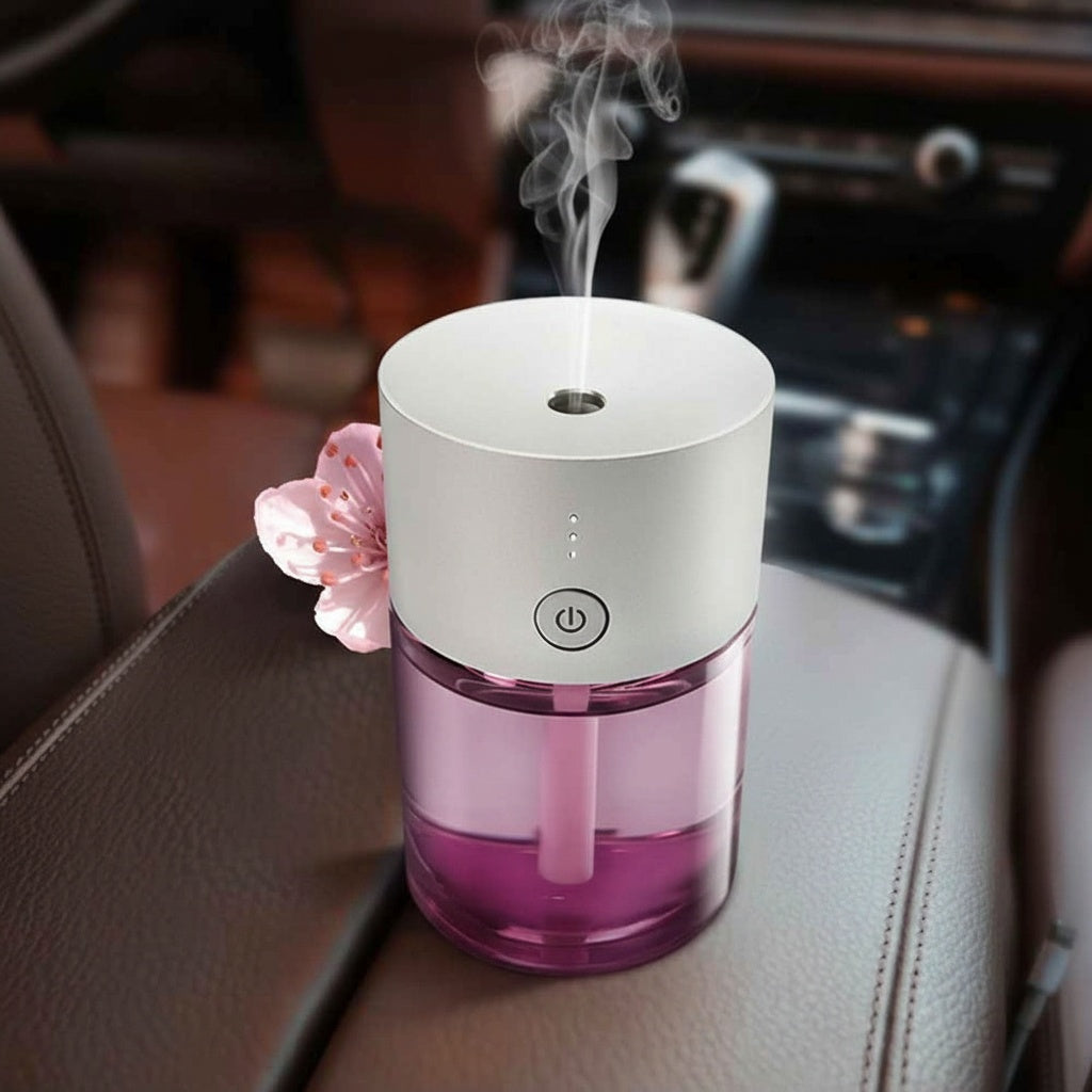 Pink and white essential oil diffuser with steam emitting on a car dashboard.