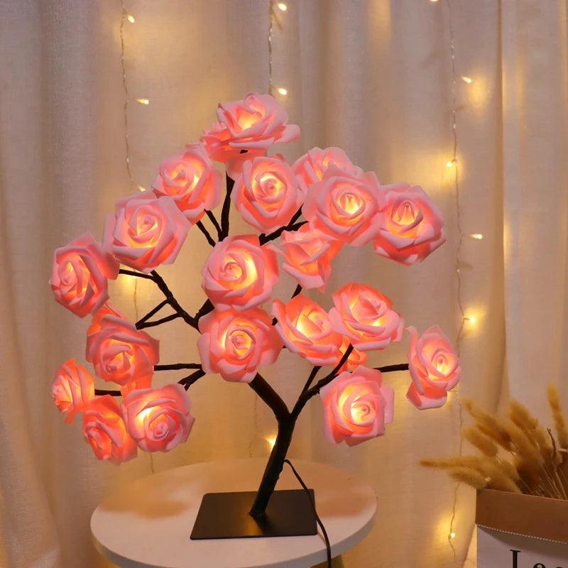 Pink rose LED flower lamp on white table with fairy lights and beige curtains