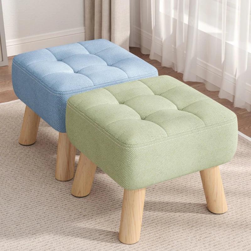 Two upholstered stools, one blue and one green, with wooden legs on a carpeted floor.