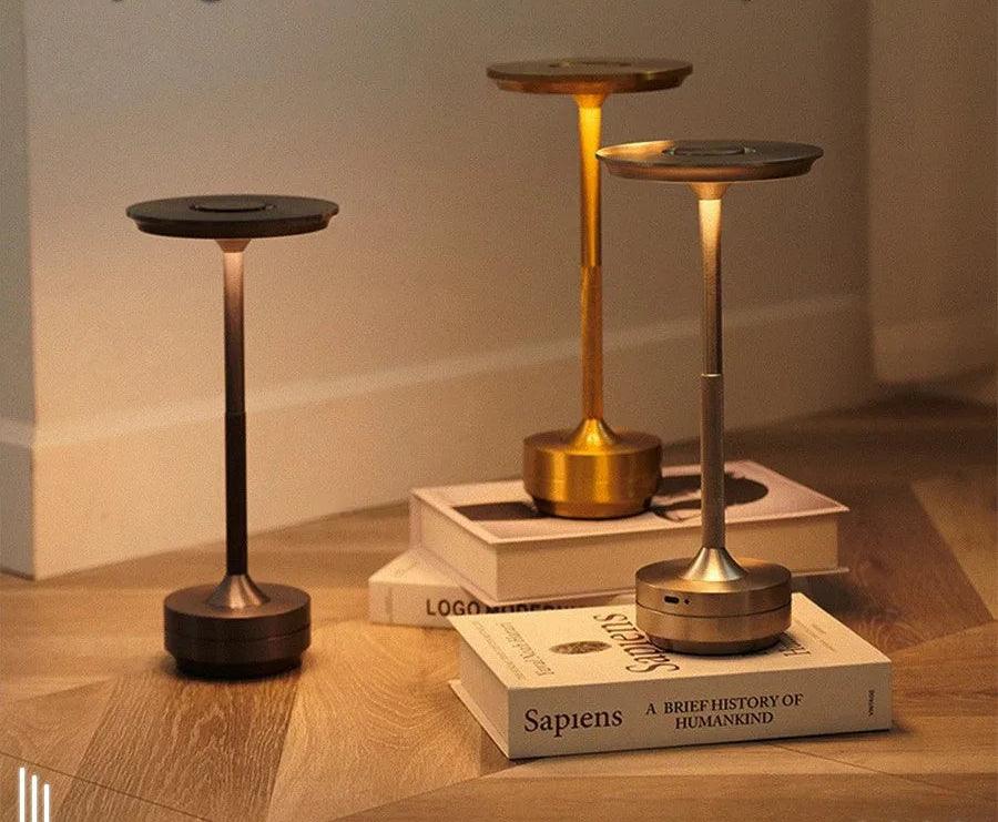 Modern wireless table lamps in black, gold, and silver on books in a cozy indoor setting