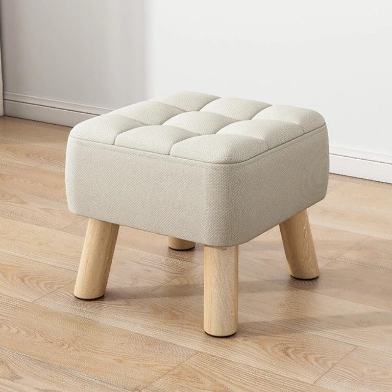 Beige ottoman with wooden legs on a wooden floor