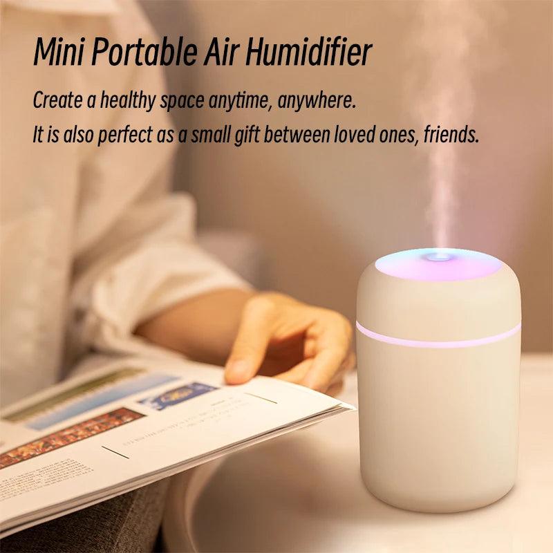 Mini portable air humidifier emitting mist on table, person reading nearby in cozy room