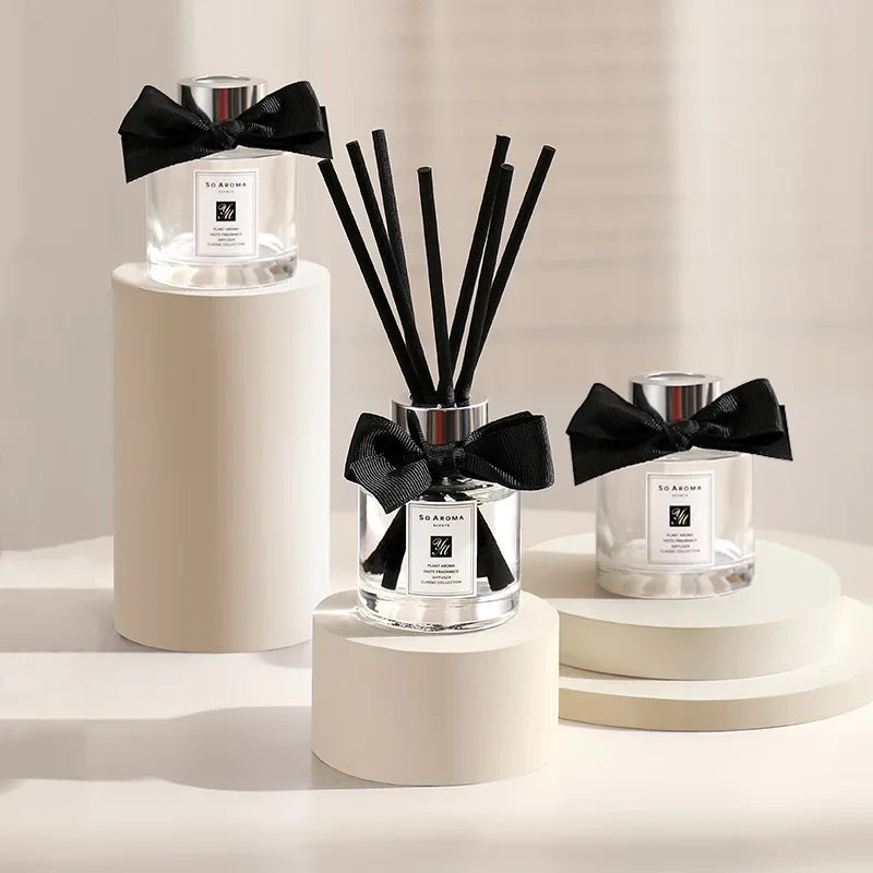 Three diffusers with black ribbons on a neutral background