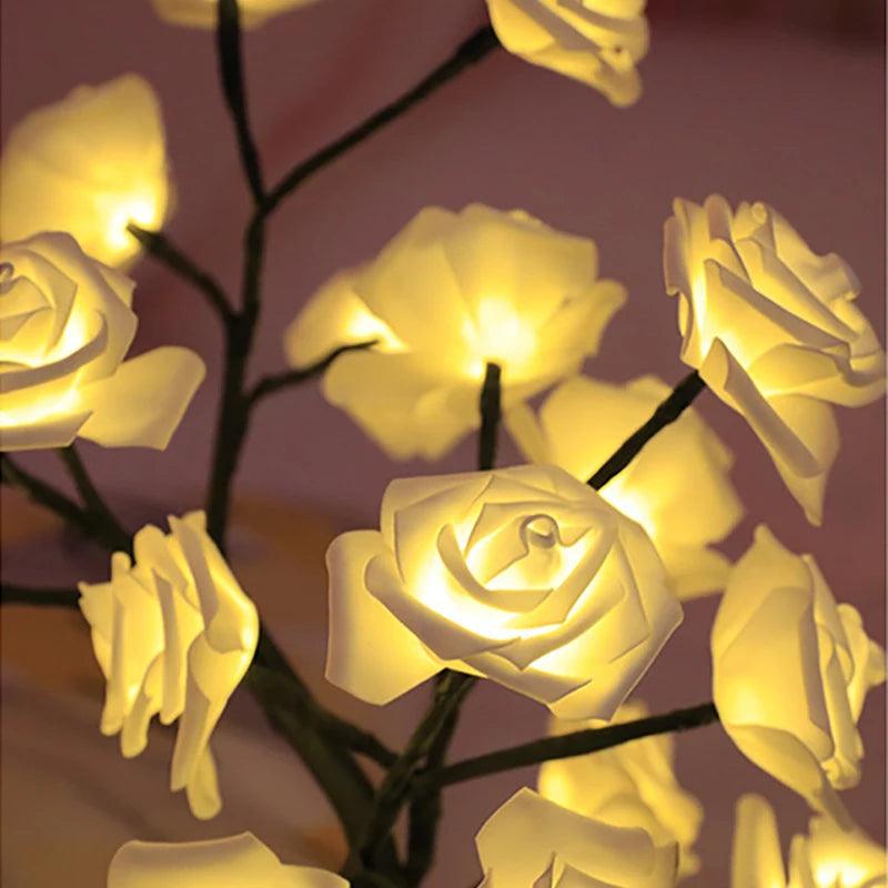 Warm white rose flower string lights glowing on dark branches indoors