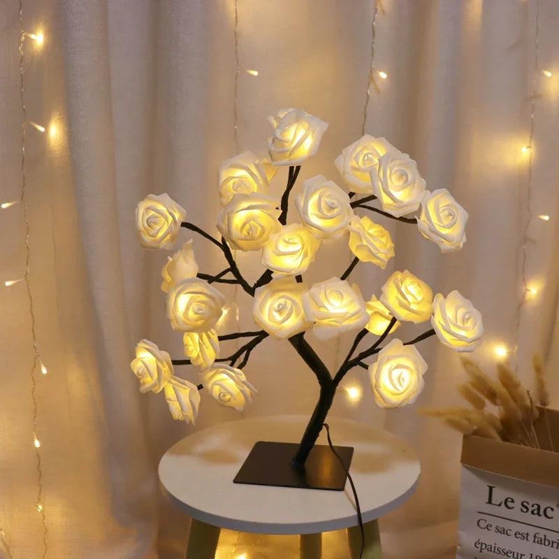 Rose flower LED night light on table with warm fairy lights and white curtains background