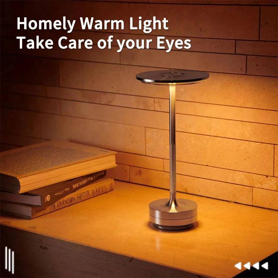 Modern LED desk lamp emits warm light on wooden table with books, brick wall background