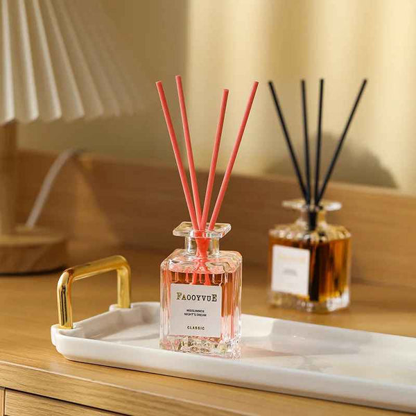 Fragrance diffuser with pink reeds on a tray in a room setting