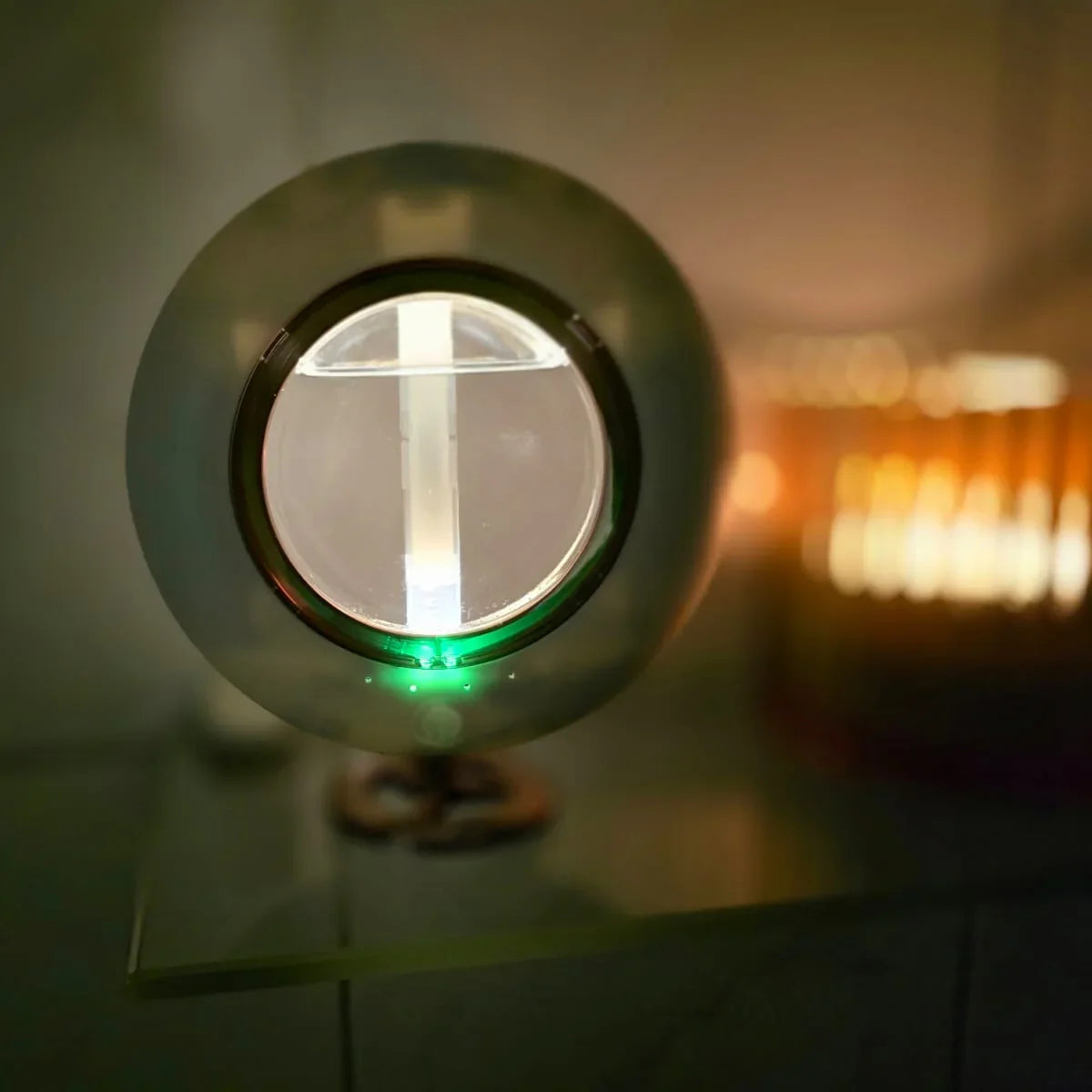 Modern spherical table lamp with green light on glass surface, warm ambient lighting